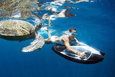 Girl using iAQUA's underwater scooter to freedive with turtles in Phuket